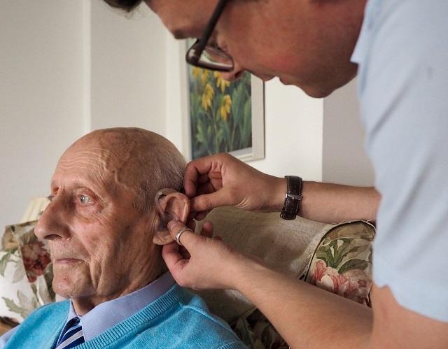 JDA staff helping man with hearing aid