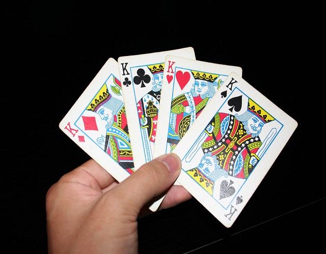 Hand holding 4 Kings playing cards