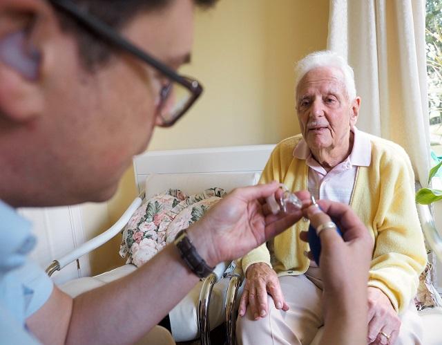 JDA staff member helping man with hearing aid 