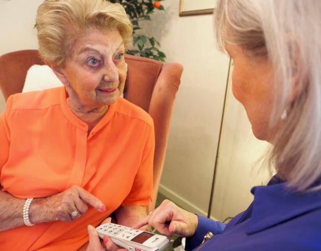 Lady looking at Yvette demonstrating mobile phone TIC home visit