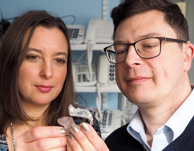 Man and woman looking at a hearing aid