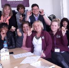A happy group of carers after the course. Group of carers all holding up rubber ears and smiling